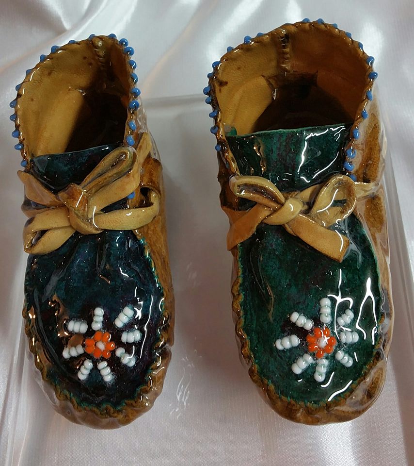 A pair of green and brown shoes with orange flowers.