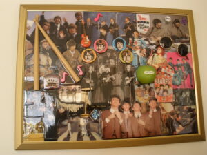 A collection of beatles memorabilia is displayed on the wall.